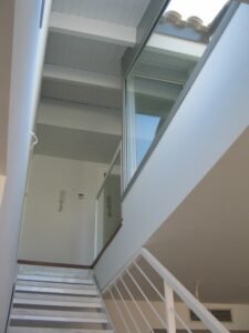 Arquitectura interior: escales modernes amb lluernari i bigues de fusta blanques.