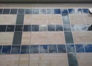 Façana d'oficines Citypark Cornellà amb vidre reflectant, panells de pedra i cel.