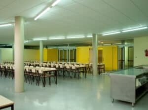 Ampli menjador o refectori modern amb taules, cadires i taulell de servei, Carmelites.