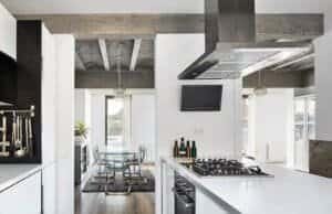 Interior Casa Ullastrell 2015: cuina moderna amb illa i sostre de formigó vist.