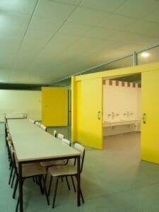 Interior d'edifici Carmelites: menjador amb taules, cadires i zona de rentamans.