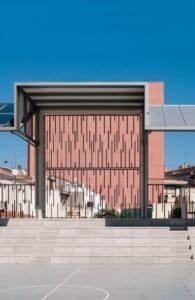 Detall constructiu façana edifici Carmelites, amb terracota vertical i pista esportiva.