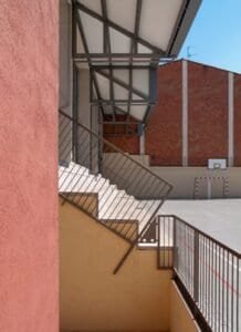 Detall constructiu: escala exterior i voladís modern en pati d'escola Carmelites.