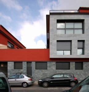 Edifici plurifamiliar a Sabadell amb façana de pedra natural i revestiment ceràmic en tons vermellosos