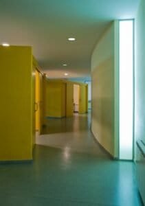 Arquitectura interior contemporània amb passadís, portes grogues i paret corba amb il·luminació. Projecte Carmelites.
