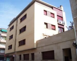 Edifici plurifamiliar a Sabadell amb façana arrebossada i pedra natural en planta baixa, amb habitatges i locals comercials